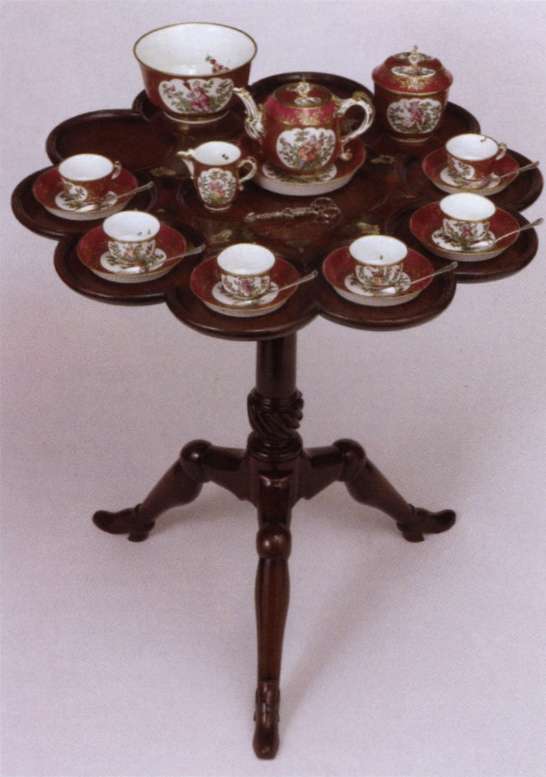 Цей чайний стіл з червоного дерева призначений для розміщення всього чайного сервізу: чашки і блюдця розміщуються ідеально на круглих зовнішніх панелях, а чайник для заварювання, підставка, молочник і срібні щипці для цукру розташовуються в центрі